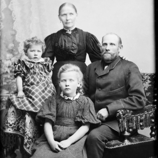 Billedet er i sorthvid og forestiller en familie bestående af far, mor og to døtre.