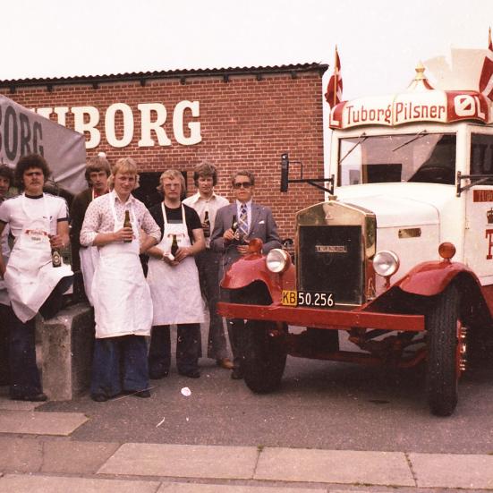 Billedet viser en flok bryggeriarbejdere i hvide forklæder ved siden af en Tuborg lastbil