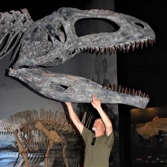 Billedet viser Steen Sigurd Andersen under et kæmpestort dinosaurkranie