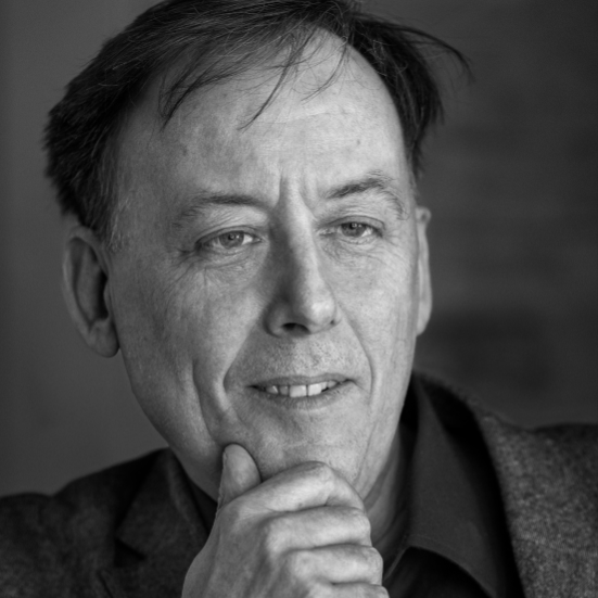 Billedet er i sort/hvid og viser Søren Schauser, der ser forbi kameraet og holder en hånd under hagen