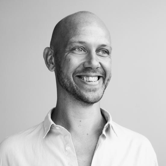 Fotoet er i sort/hvid og viser en smilende Simon Krohn med en opknappet skjorte