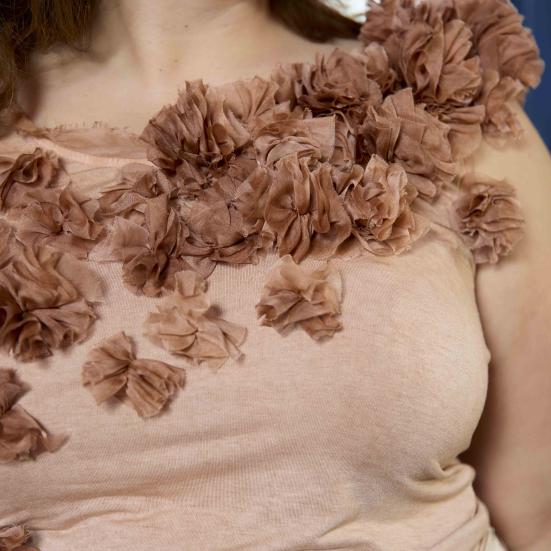 Billedet forestiller en kvinde iført en bluse i en svag lyserød farve.