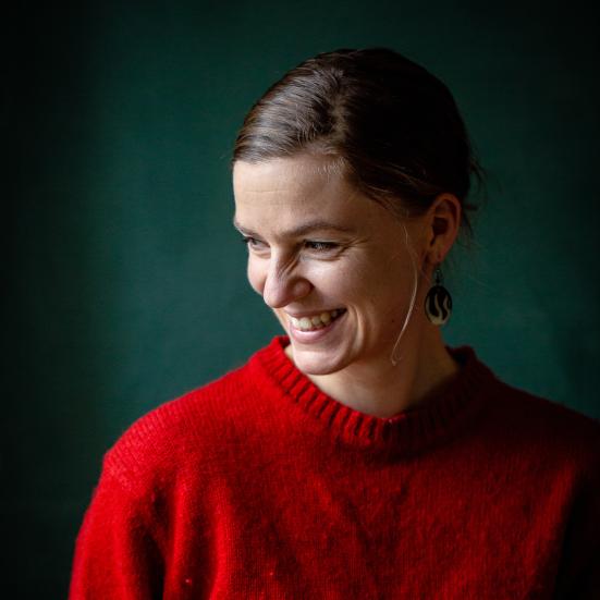Fotoet viser en smilende Anne Valbjørn Odgaard iført en rød sweater