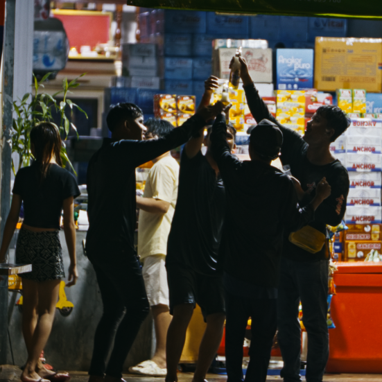 Billedet viser en gruppe mennesker, der skåler med hinanden foran en butik