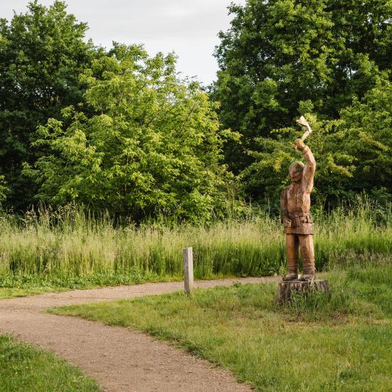 Billedet viser en sti, der forsvinder mellem træer og buske