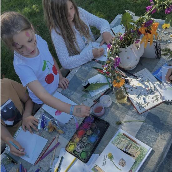 Fotoet viser to børn, der er fordybet i at male planter