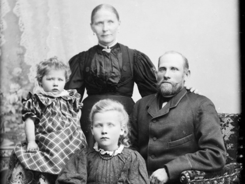 Billedet er i sorthvid og forestiller en familie bestående af far, mor og to døtre.