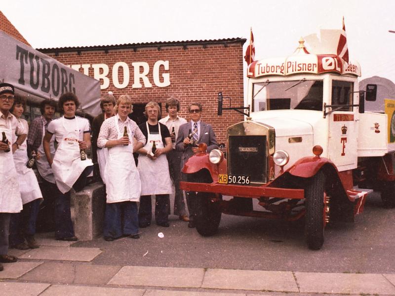 Billedet viser en flok bryggeriarbejdere i hvide forklæder ved siden af en Tuborg lastbil