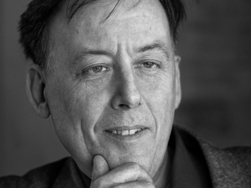 Billedet er i sort/hvid og viser Søren Schauser, der ser forbi kameraet og holder en hånd under hagen