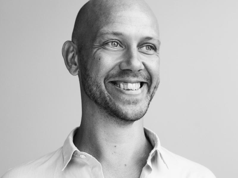 Fotoet er i sort/hvid og viser en smilende Simon Krohn med en opknappet skjorte