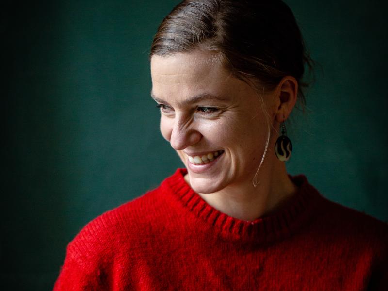 Fotoet viser en smilende Anne Valbjørn Odgaard iført en rød sweater