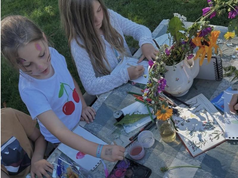 Fotoet viser to børn, der er fordybet i at male planter