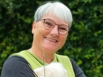 Billedet viser en smilende Mette Albæk med et strikketøj i hænderne