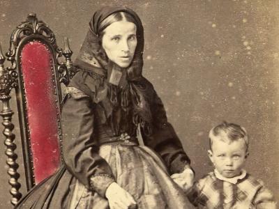 Billedet er et gammelt, sort/hvid foto af en kvinde med et lille barn