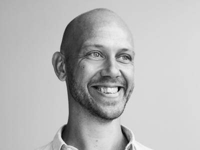 Fotoet er i sort/hvid og viser en smilende Simon Krohn med en opknappet skjorte