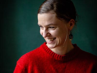 Fotoet viser en smilende Anne Valbjørn Odgaard iført en rød sweater