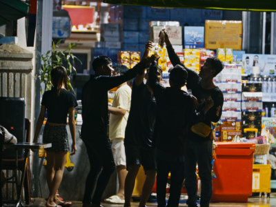 Billedet viser en gruppe mennesker, der skåler med hinanden foran en butik