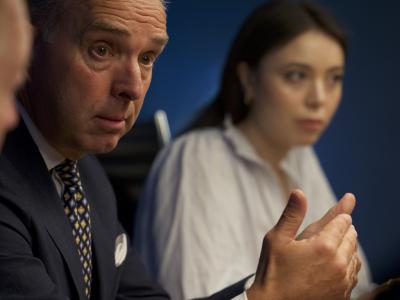 Billedet viser en mand i jakkesæt, der sidder ved siden af en kvinde i en hvid skjorte