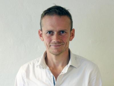 Billedet viser en smilende Jacob Tybjerg iført en hvid skjorte
