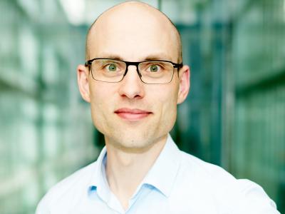 Billedet viser en smilende David Hopmann foran en sløret baggrund