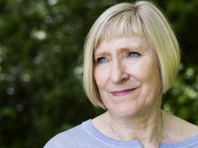 Billedet viser en smilende Pernille Juhl foran et grønt buskads