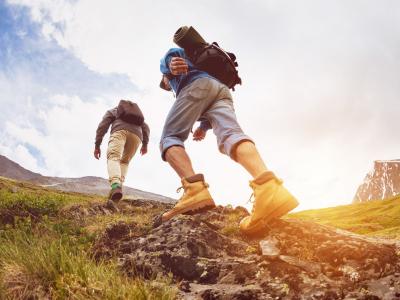Vandrere på vej op ad en stenet sti i bjerglandskab.