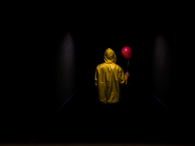 Person med gul regnjakke og rød ballon set bagfra