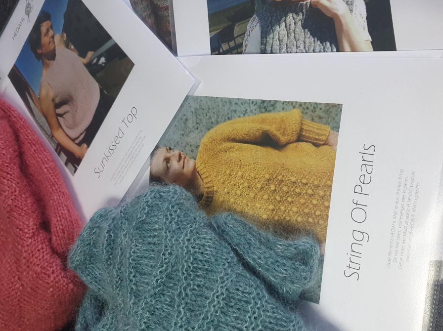 Fotoet viser strikketøj, som ligger oven på forskellige strikkeopskrifter