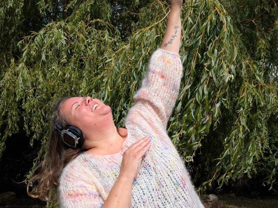 Billedet forestiller en dansende kvinde med høretelefoner på.
