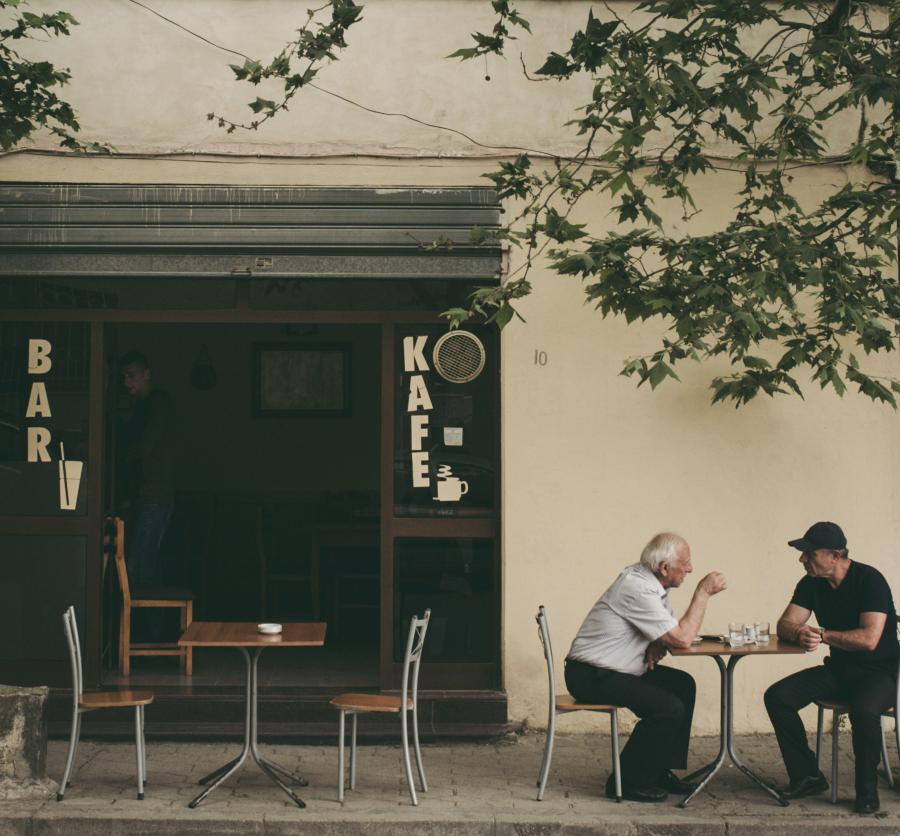To ældre mennesker i samtale ude foran en café
