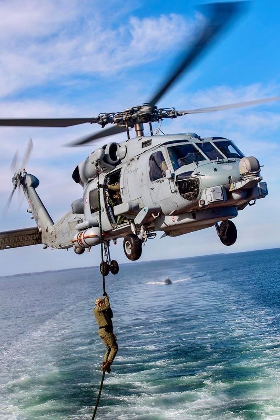 En bomstærk helikopter er ved enten at smide en soldat ud eller samle ham op. Han hænger i hvert fald i et reb eller meget tyk snor