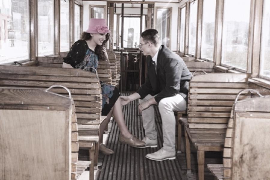 En mand og en kvinde i tøj fra 1940erne sidder i en sporvogn.