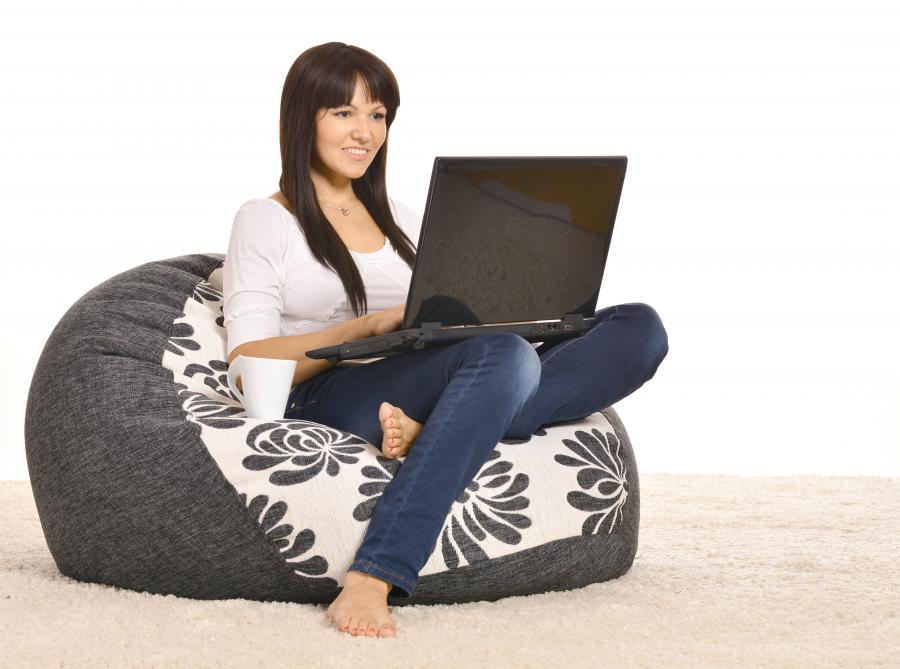 Billedet forestiller en kvinde, der sidder mageligt i en sækkestol. På skødet har hun en computer, og hun ser smilende og interesseret på skærmen.