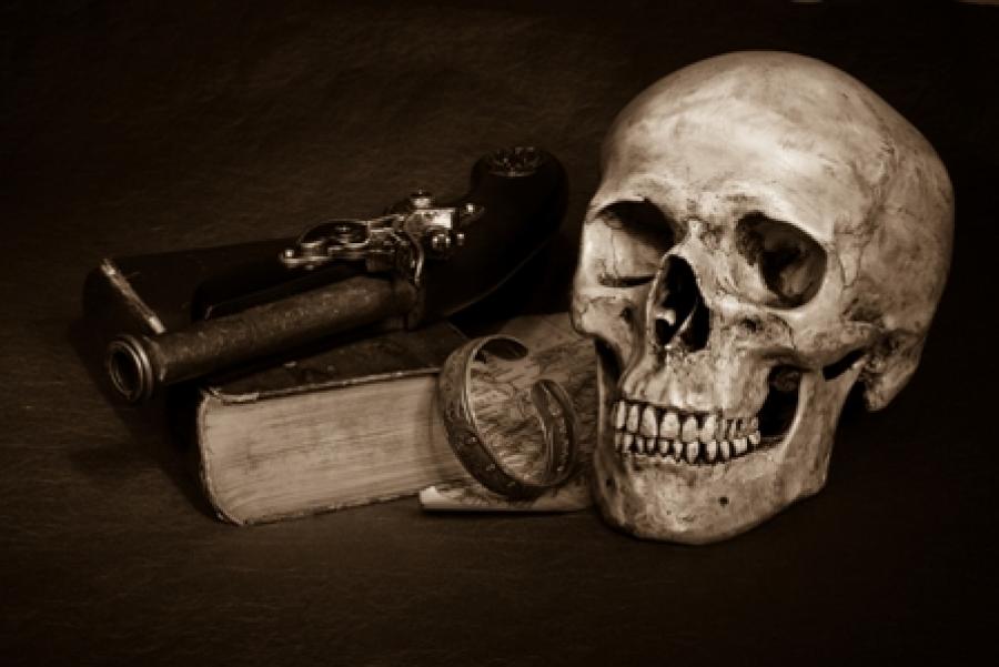 Et stemningsfyldt billede af en gammel bog, en pistol og et kranie.