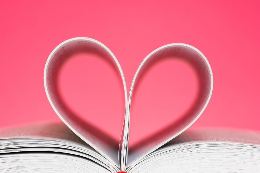 Billedet forestiller en bog, hvor siderne er foldet, så de danner et hjerte. Baggrunden er lyserød.
