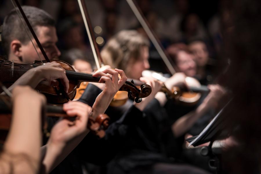 Nærbillede af pænt klædte violister ved klassisk koncert. Stemningen er lettere forførende