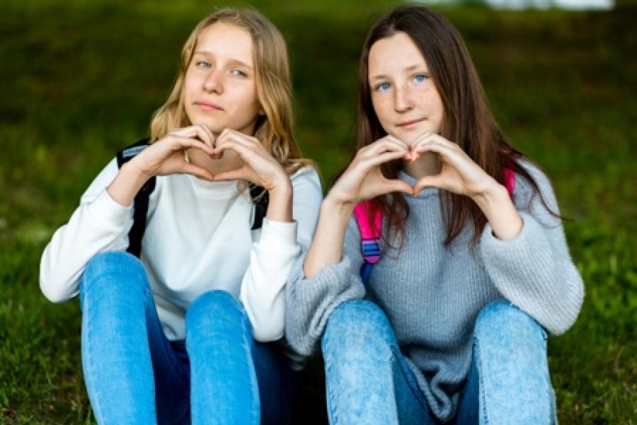 To piger laver hjertetegn med deres hænder.